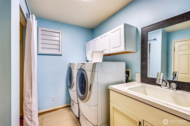 laundry area with a sink, baseboards, washing machine and dryer, and cabinet space