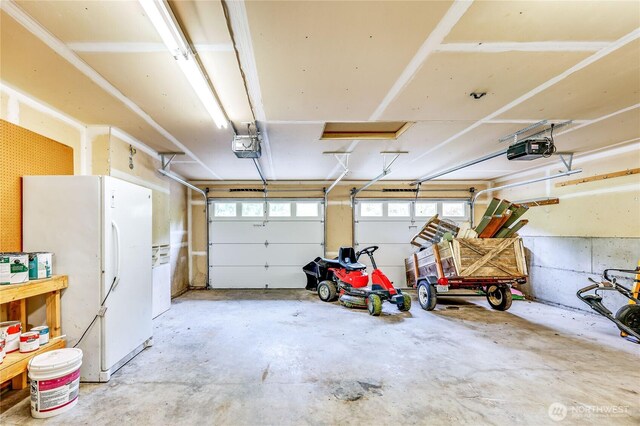 garage with freestanding refrigerator and a garage door opener