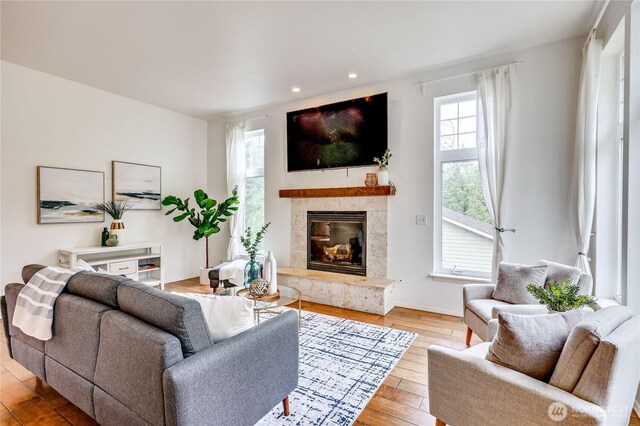 living room with a high end fireplace, baseboards, recessed lighting, and hardwood / wood-style floors