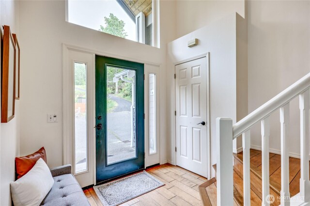 foyer entrance featuring a high ceiling, light wood-type flooring, and stairs