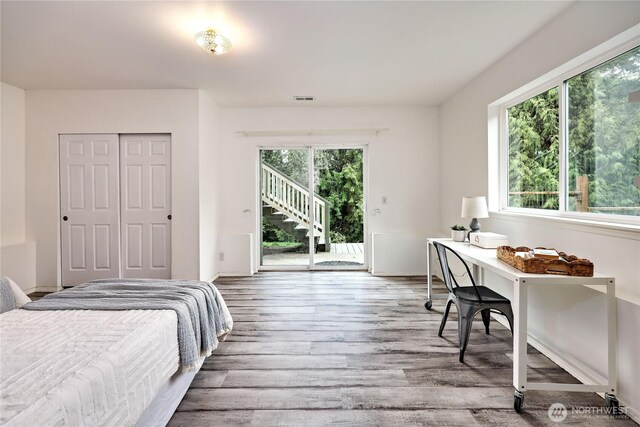 bedroom with access to outside, a closet, wood finished floors, and visible vents