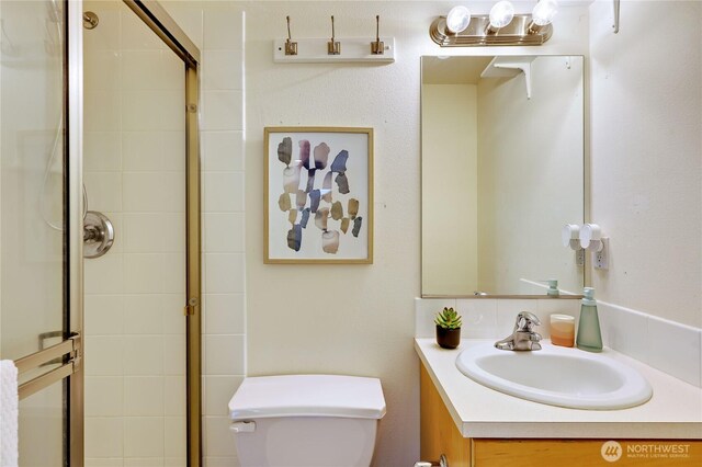 bathroom featuring vanity, a tile shower, and toilet