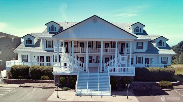 view of front facade with stairway, covered porch, and uncovered parking