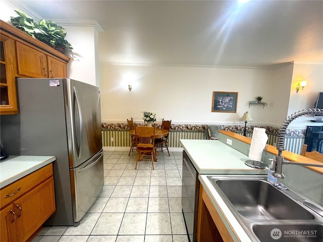 kitchen featuring crown molding, appliances with stainless steel finishes, brown cabinetry, and a sink
