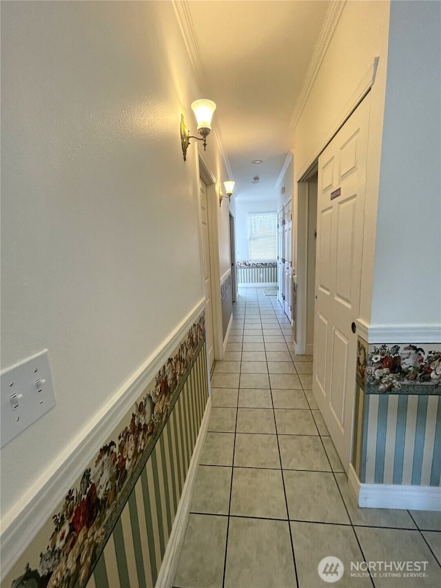 hall featuring wallpapered walls, baseboards, light tile patterned flooring, and ornamental molding