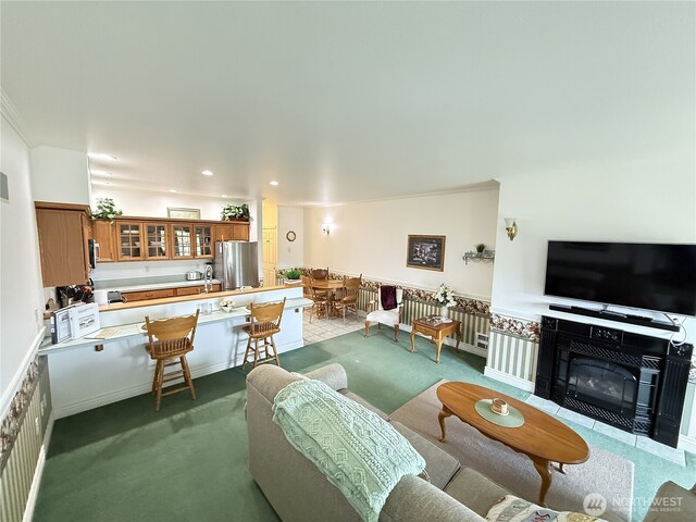carpeted living room with a sink, a fireplace with flush hearth, and recessed lighting