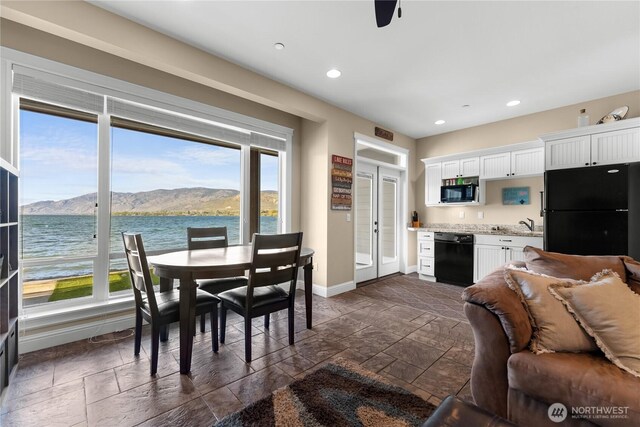 interior space featuring recessed lighting, stone tile flooring, a water and mountain view, and baseboards