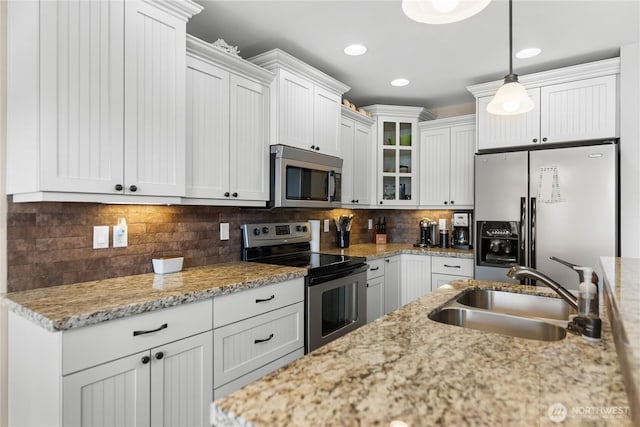 kitchen with stainless steel appliances, a sink, decorative light fixtures, glass insert cabinets, and white cabinetry
