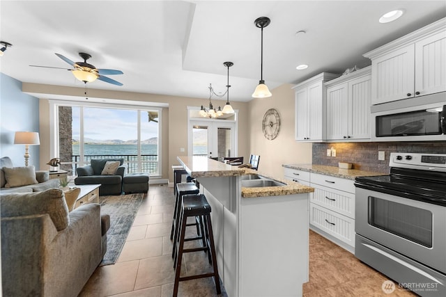 kitchen with tasteful backsplash, stainless steel electric range oven, open floor plan, a kitchen bar, and white cabinetry