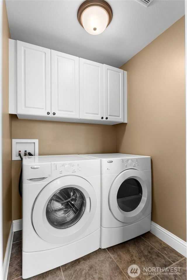 laundry room with dark tile patterned floors, baseboards, washer and dryer, and cabinet space