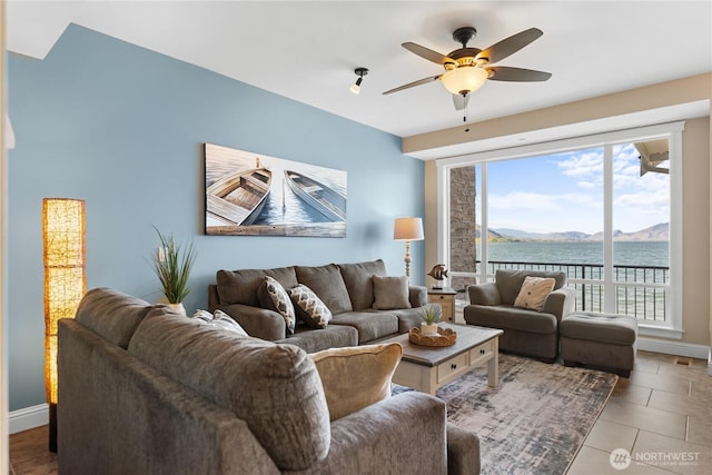 living room with a ceiling fan, baseboards, and a water and mountain view