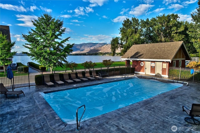 pool with a patio, fence, and a water and mountain view