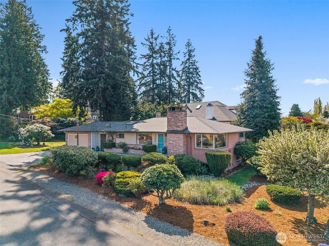 view of front facade with a chimney, an attached garage, and concrete driveway