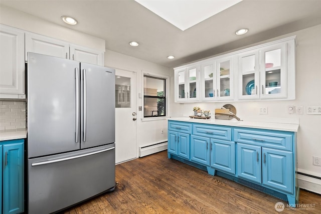 kitchen featuring a baseboard heating unit, blue cabinets, glass insert cabinets, light countertops, and freestanding refrigerator