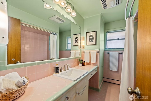 bathroom featuring a baseboard heating unit, tile patterned floors, visible vents, and tile walls
