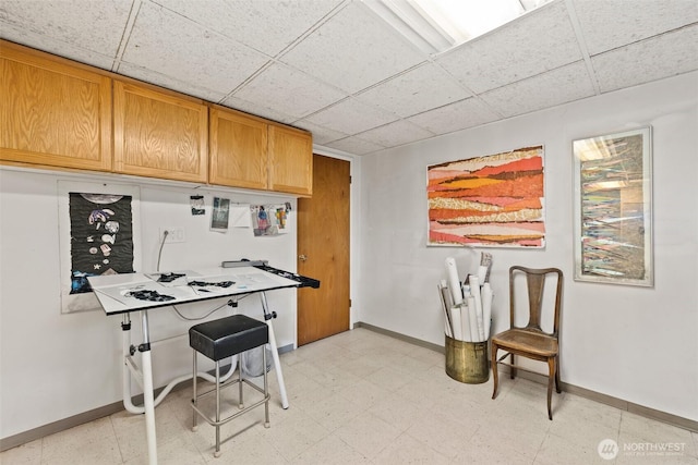 kitchen with light floors, baseboards, and a drop ceiling