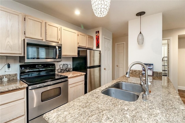 kitchen featuring a sink, light brown cabinetry, pendant lighting, stainless steel appliances, and light stone countertops