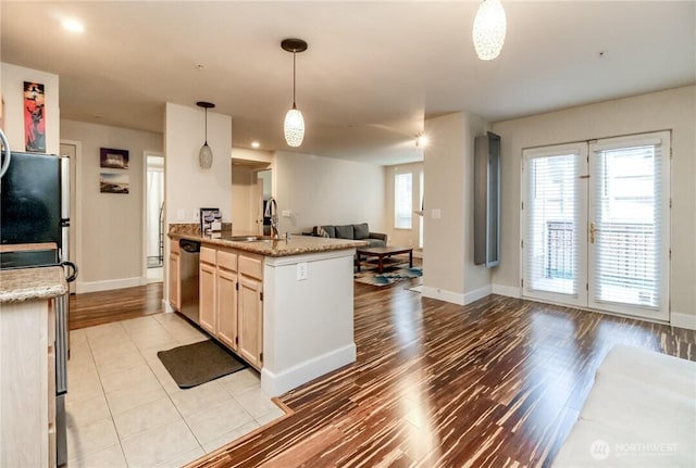 kitchen with open floor plan, dishwasher, baseboards, and light wood-style flooring