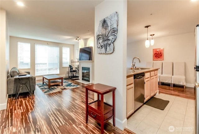 interior space with stainless steel dishwasher, open floor plan, a sink, and baseboards