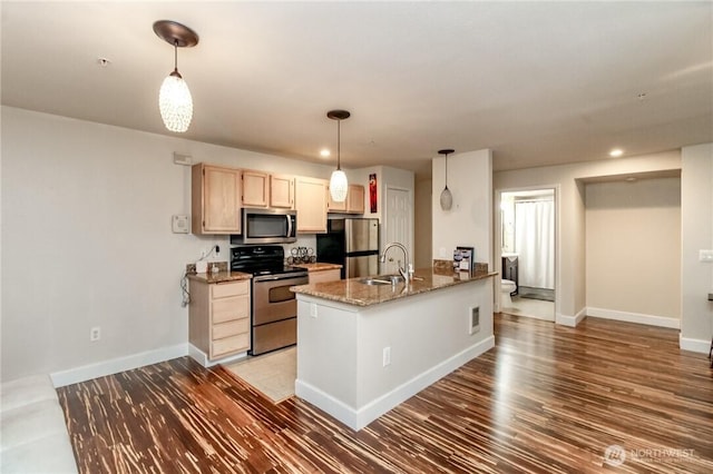 kitchen with a peninsula, baseboards, a sink, and appliances with stainless steel finishes