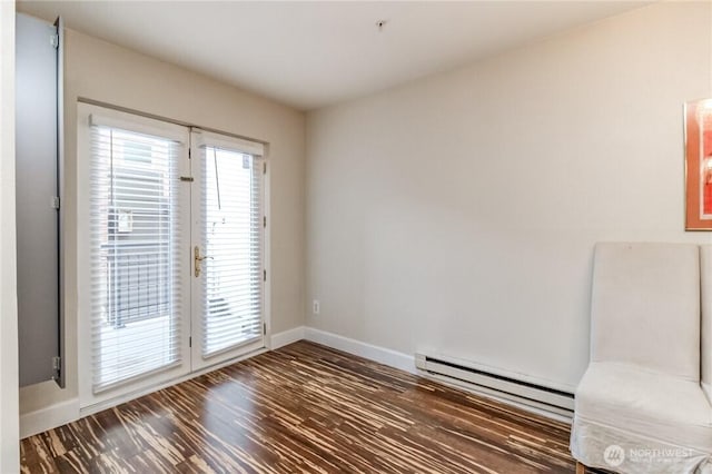 unfurnished room featuring baseboard heating, baseboards, and wood finished floors