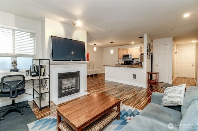 living room with dark wood-style flooring, visible vents, baseboards, recessed lighting, and a tile fireplace