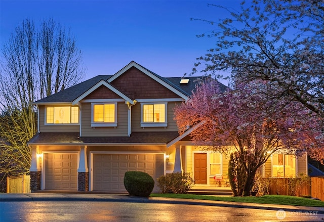 craftsman inspired home featuring a garage, driveway, stone siding, and fence