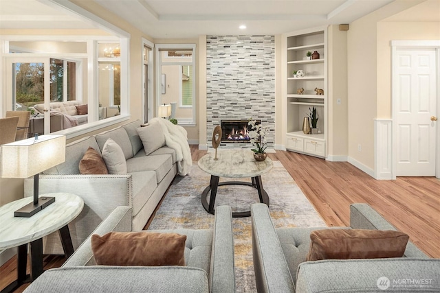 living room featuring a fireplace, baseboards, light wood-style floors, and a wealth of natural light