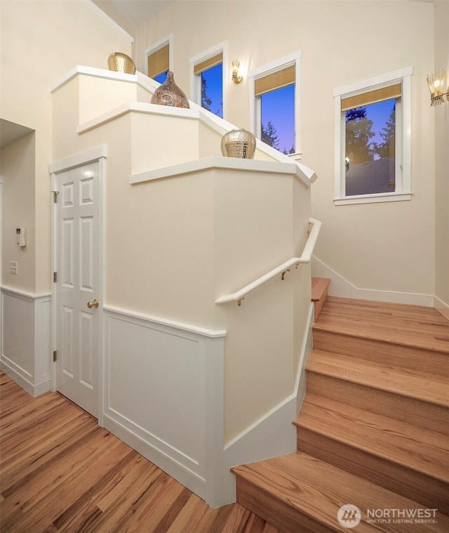 stairway featuring wood finished floors and wainscoting