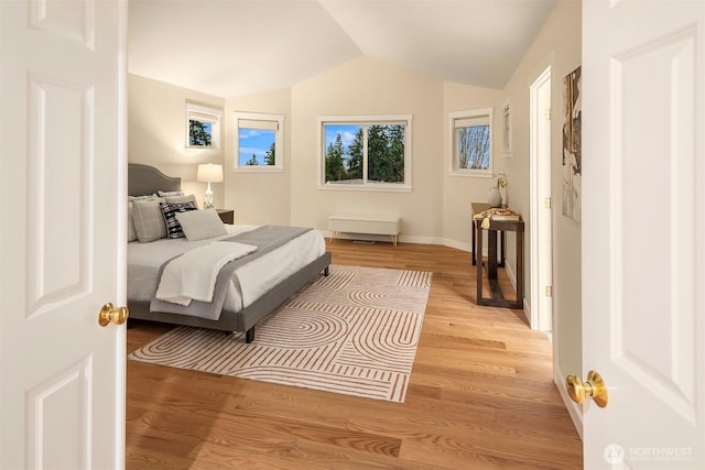 bedroom featuring baseboards, lofted ceiling, and light wood-type flooring