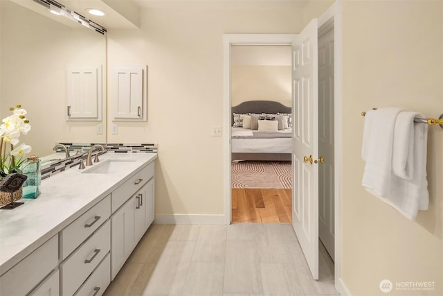 ensuite bathroom featuring ensuite bath, baseboards, and vanity