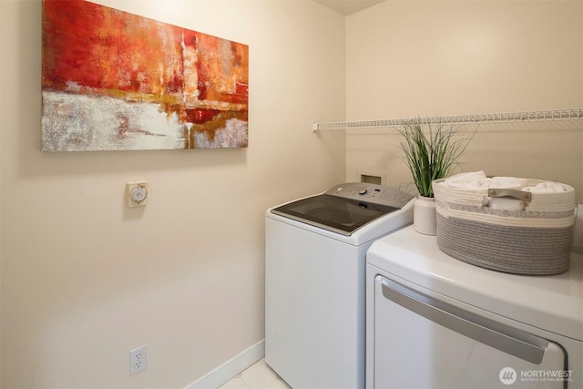 clothes washing area with washing machine and dryer, baseboards, and laundry area