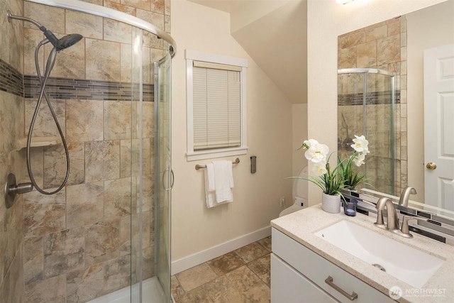 full bath with baseboards, vanity, and a stall shower