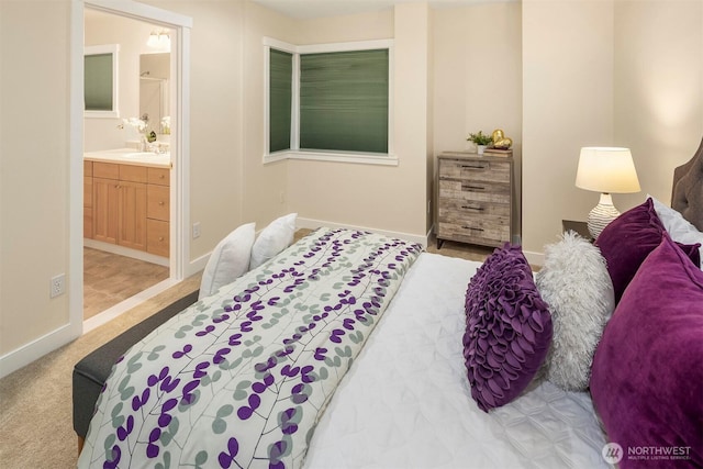 bedroom featuring baseboards, carpet flooring, ensuite bathroom, and a sink