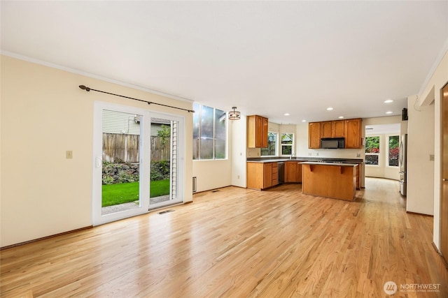 kitchen featuring black microwave, a center island, light wood-type flooring, and brown cabinets