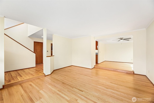 spare room with light wood-style floors, ornamental molding, and a ceiling fan