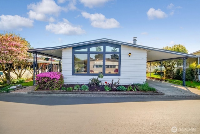view of side of property with concrete driveway and an attached carport