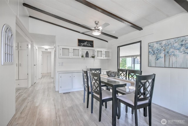 dining space featuring vaulted ceiling with beams, a ceiling fan, and light wood-style flooring