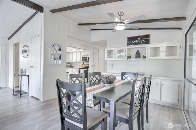 dining space featuring lofted ceiling with beams, light wood finished floors, and ceiling fan