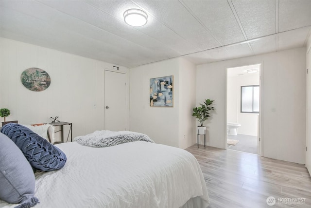 bedroom featuring ensuite bath and wood finished floors