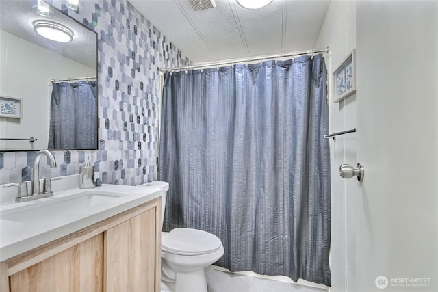 bathroom with vanity, toilet, a textured ceiling, wallpapered walls, and visible vents