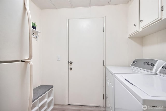 laundry room featuring independent washer and dryer, light wood-style floors, and cabinet space