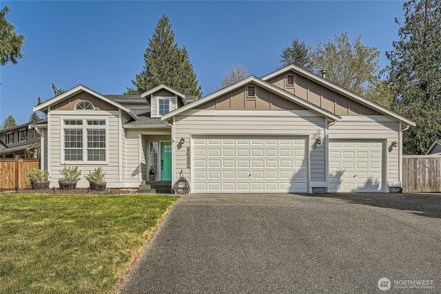 view of front facade featuring board and batten siding, a front lawn, fence, and aphalt driveway