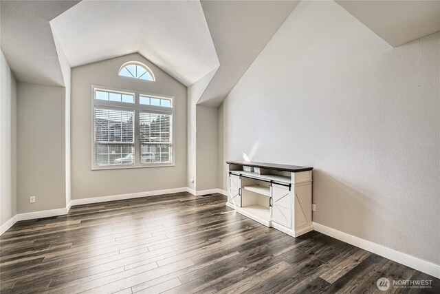 additional living space with lofted ceiling, baseboards, and dark wood finished floors