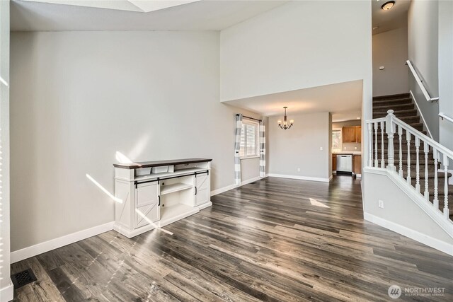 unfurnished living room featuring dark wood finished floors, baseboards, a chandelier, stairway, and high vaulted ceiling