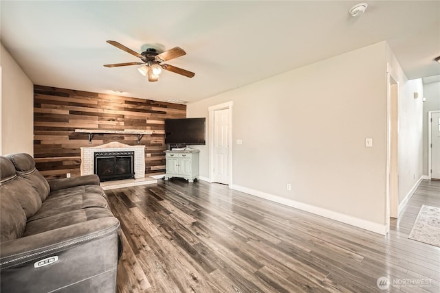 unfurnished living room featuring a fireplace, wooden walls, a ceiling fan, and dark wood-style flooring