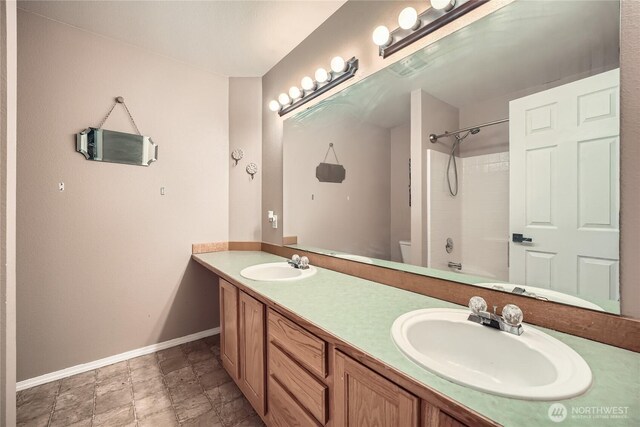 full bathroom featuring double vanity, toilet, baseboards, and a sink