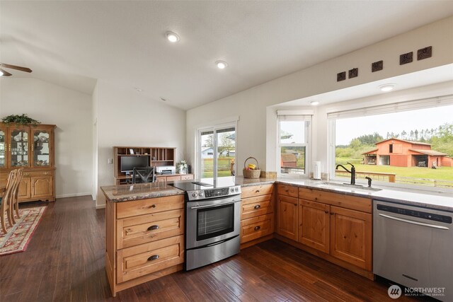 kitchen with stainless steel appliances, a sink, vaulted ceiling, a peninsula, and dark wood-style floors