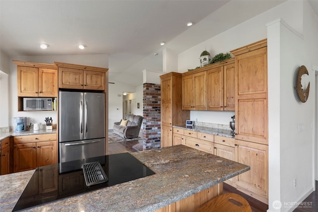 kitchen with appliances with stainless steel finishes, vaulted ceiling, stone countertops, dark wood-style flooring, and a breakfast bar