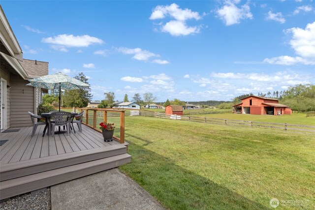 view of yard featuring a wooden deck, outdoor dining area, and an outbuilding